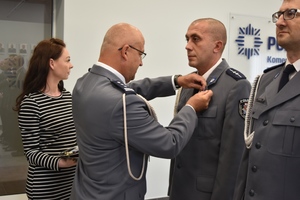 Komendant przypina policjantowi medal.