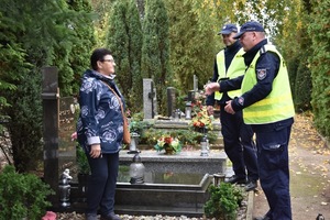 Policjanci na cmentarzu rozmawiają z seniorką.