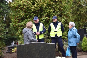 Policjanci na cmentarzu rozmawiają z seniorkami.
