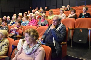 Seniorzy siedzą na widowni kinoteatru.