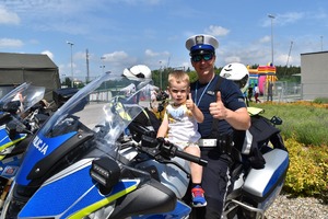 Policjant i chłopiec siedzą na motocyklu.