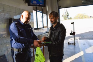 Policjant wręcza kierującemu kamizelkę odblaskową oraz inne upominki.