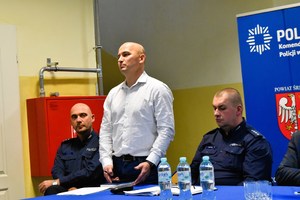 Policjant stoi i zwraca się do uczestników debaty.