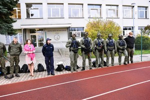 Policjanci, żołnierze i Pani Dyrektor szkoły, stoją na boisku.