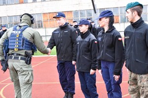 Policjant i uczniowie na boisku szkolnym.