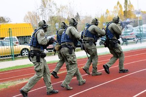 Policjanci z Grupy Realizacyjnej podczas symulacji, na boisku szkolnym.