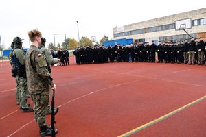 Policjanci i uczniowie na boisku szkolnym.