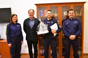 Policjanci i Dyrektor szkoły stoją i pozują do pamiątkowego zdjęcia.