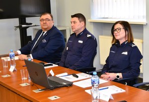 Osoby siedzą za stołem konferencyjnym.