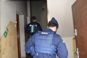 Dwóch policjantów idzie po schodach na klatce schodowej.